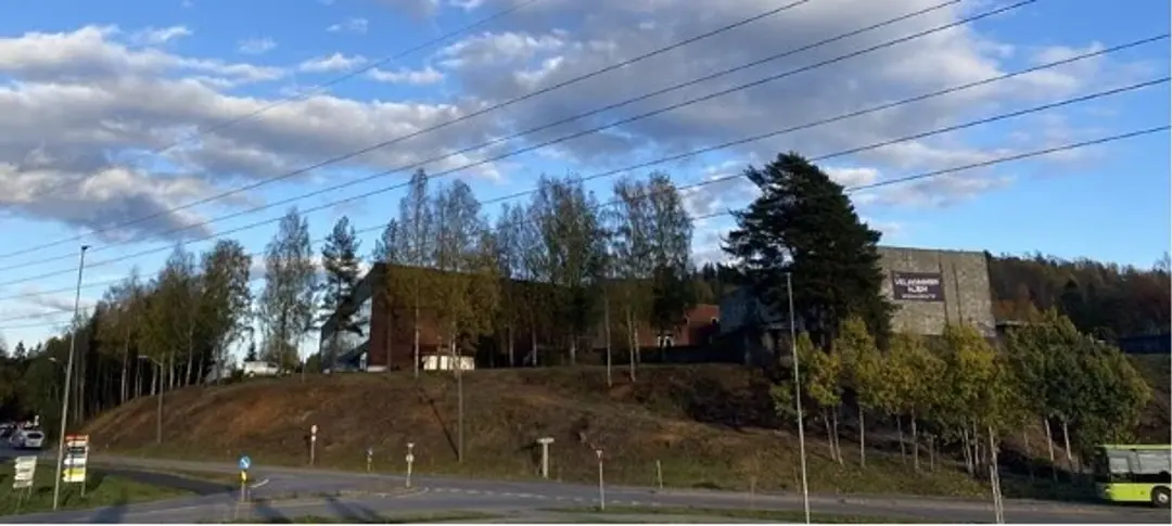 Stort bygg på en topp bak flere trær.